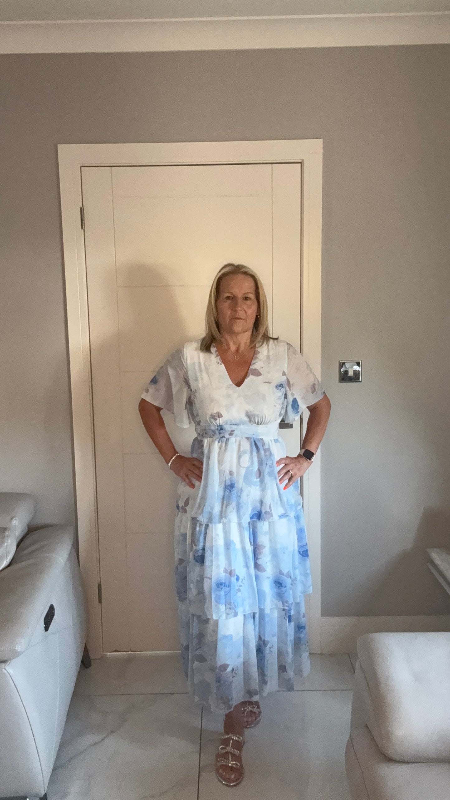 Woman in a floral dress standing in a room with a neutral color scheme.