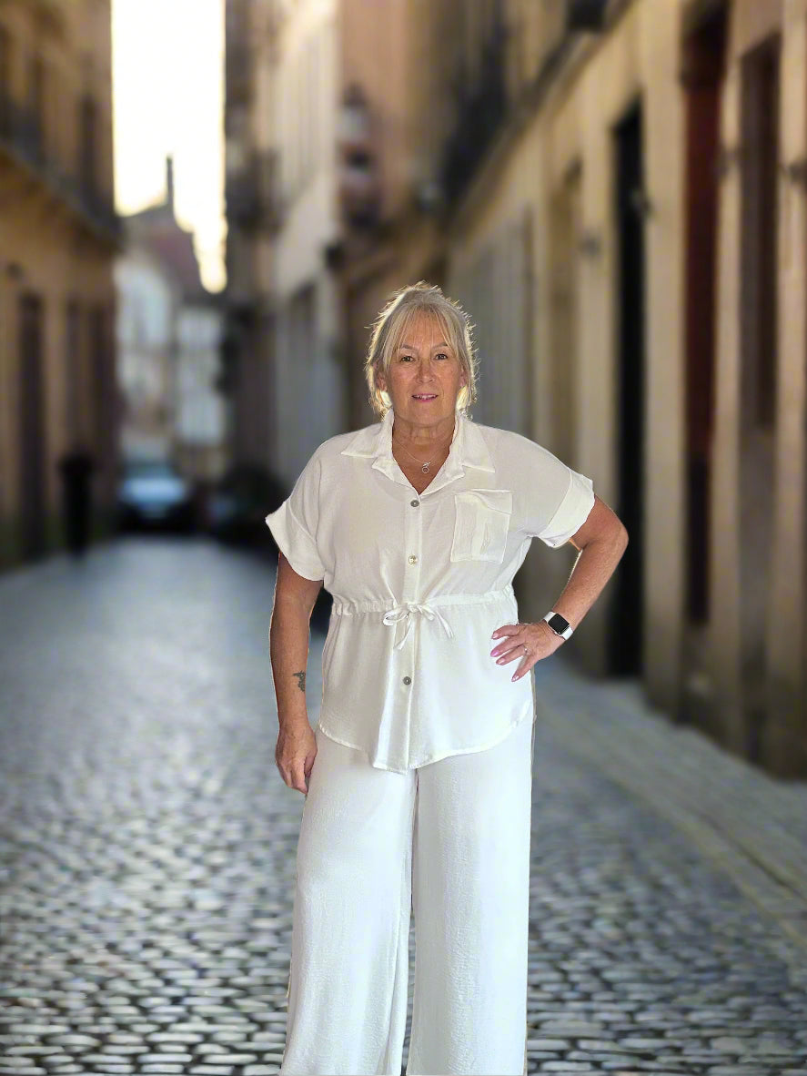 Woman in a white outfit standing on a cobblestone street