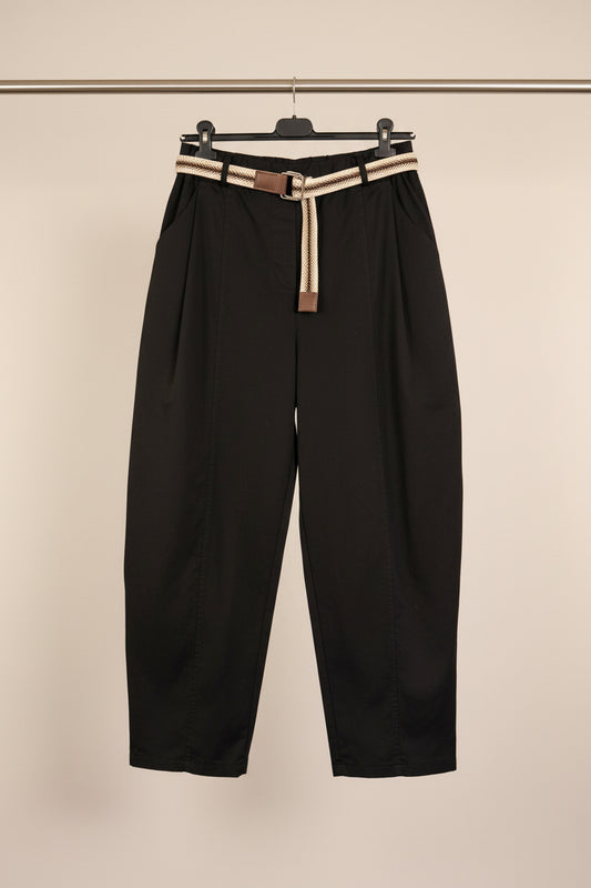 Black wide-leg cropped pants with pleated front details, hanging on a black hanger with a beige and black woven belt, against a white paneled door.