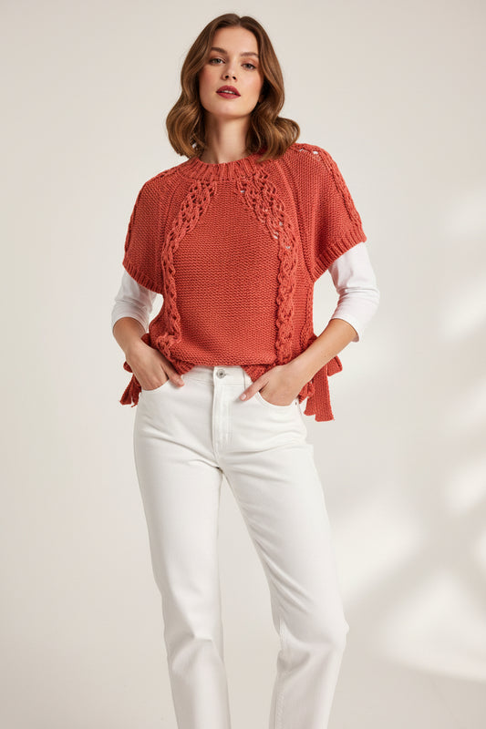 hand-knit short-sleeve top with a a coral textured lace panels and side ties, hanging on a black hanger against a white paneled background.