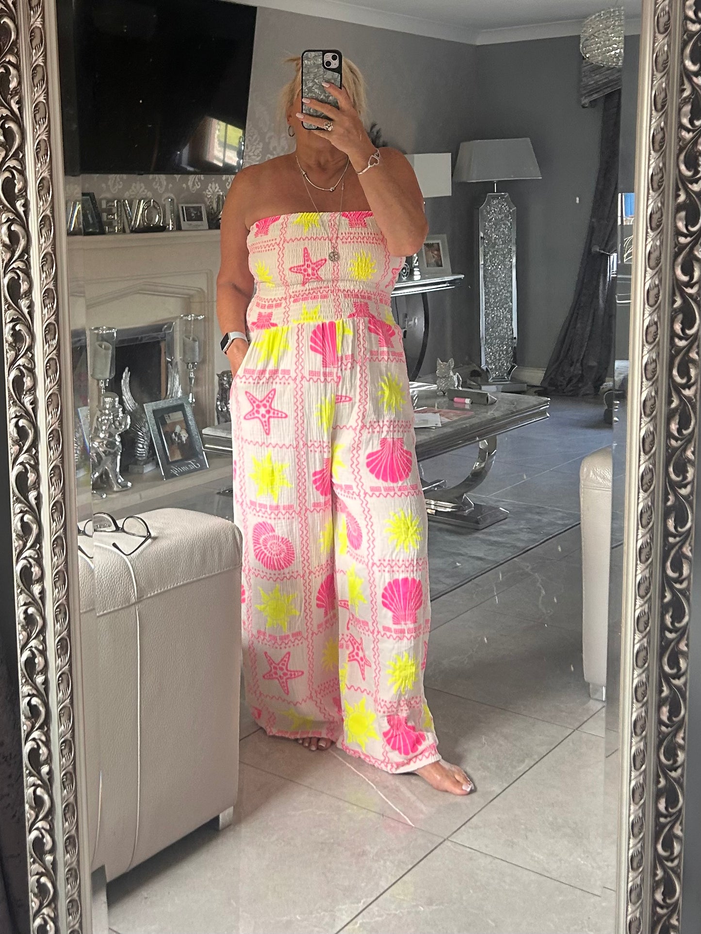 Person wearing a colourful jumpsuit with shell patterns in a room.