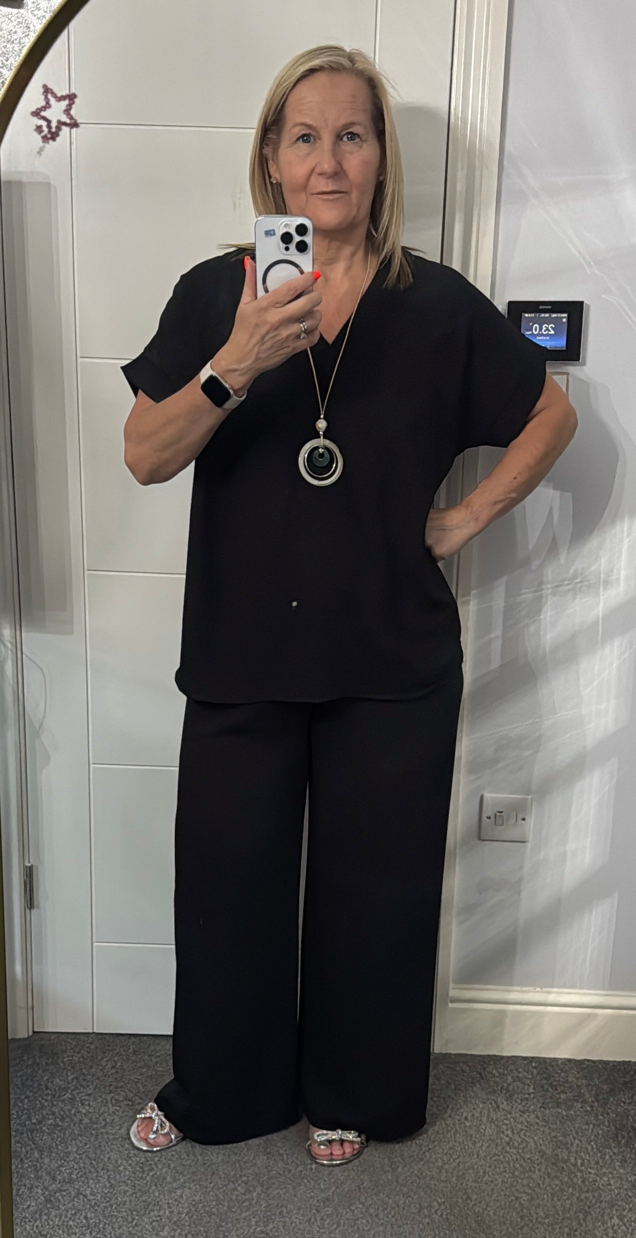 Woman taking a mirror selfie wearing a black outfit,
