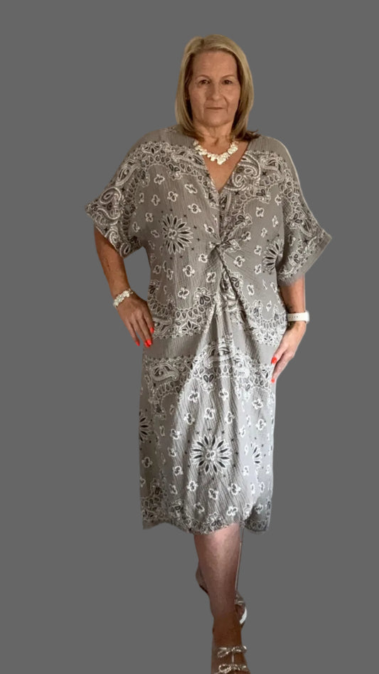 Woman in a patterned dress standing in a a grey background