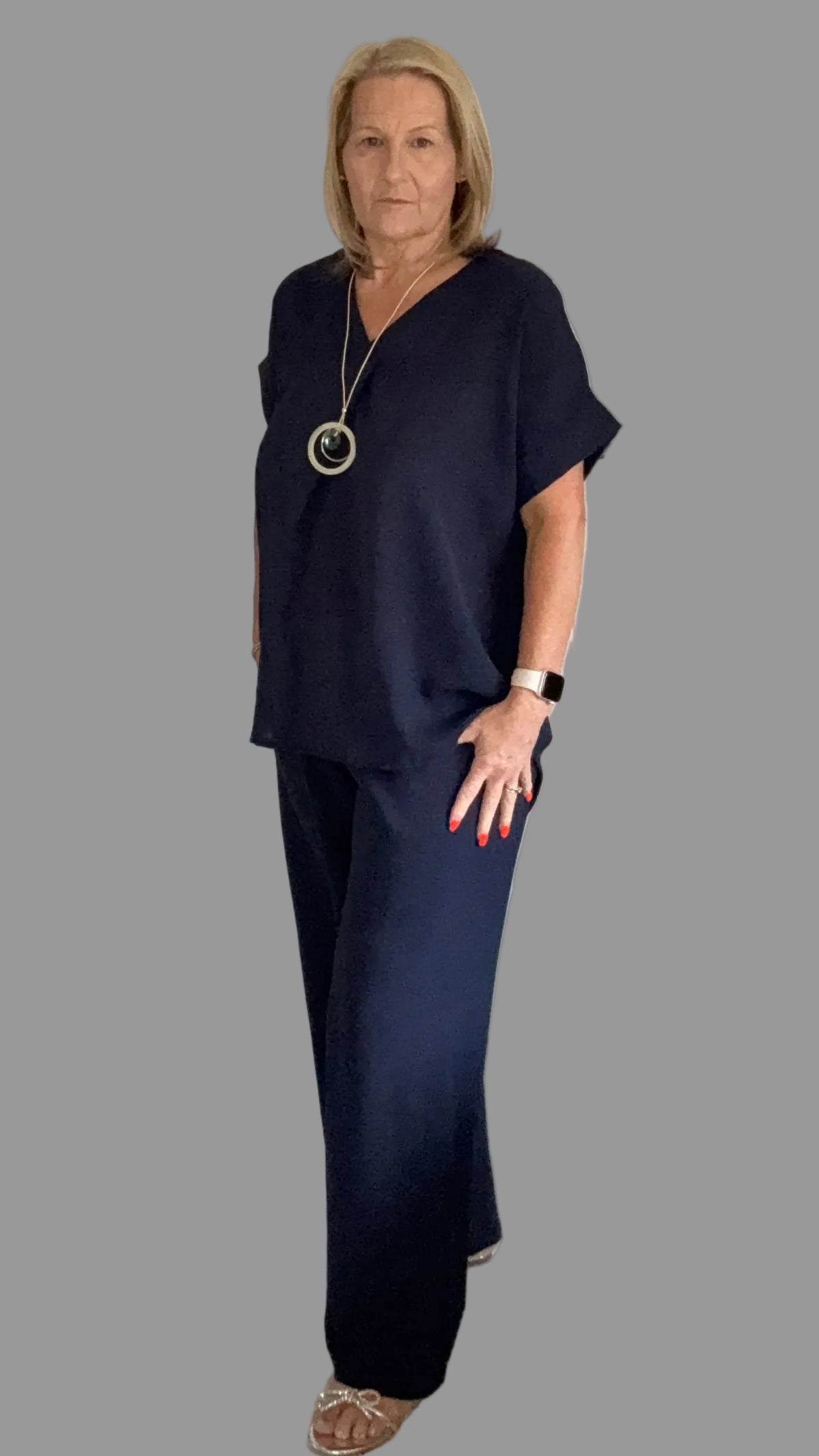 Woman in a navy outfit standing in a room with Grey background