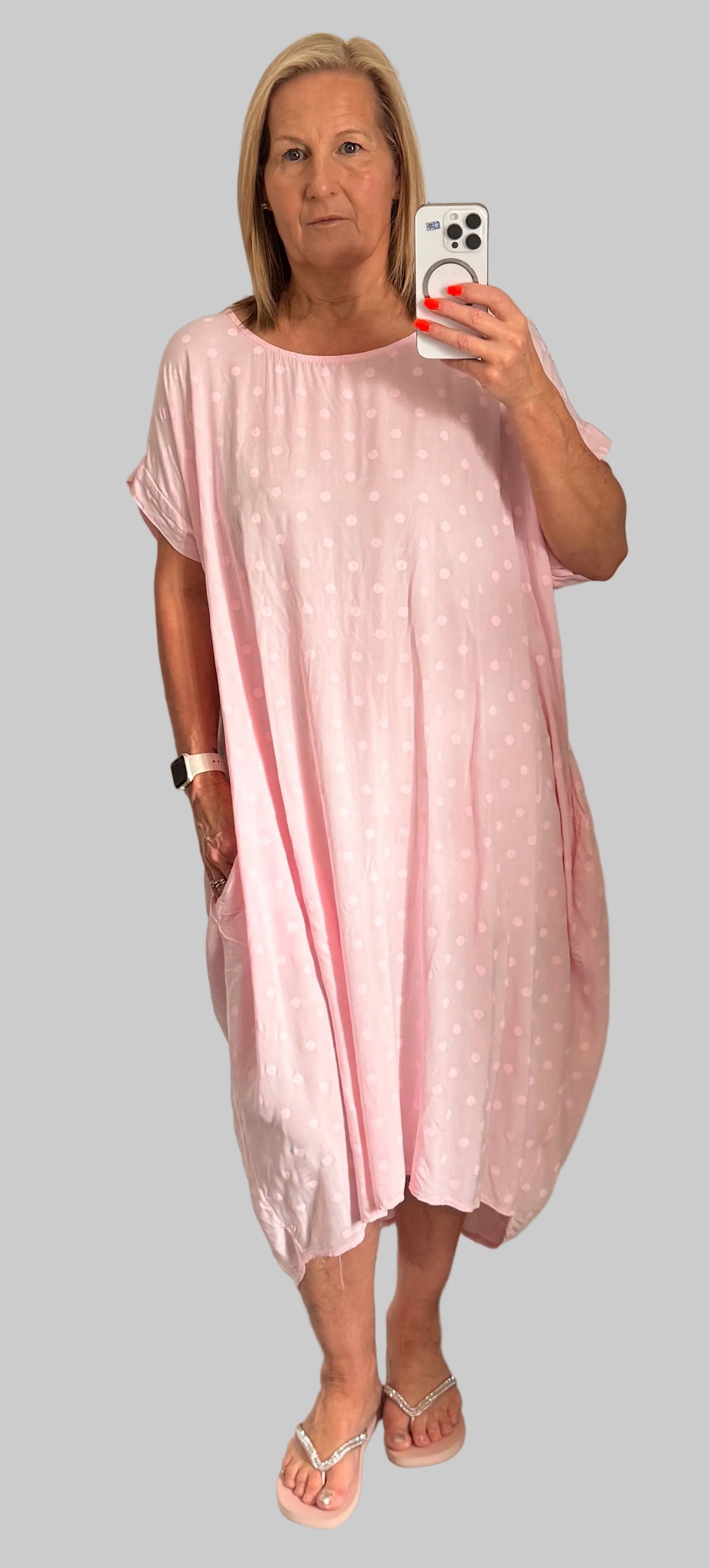 Woman taking a mirror selfie wearing a pink dress.