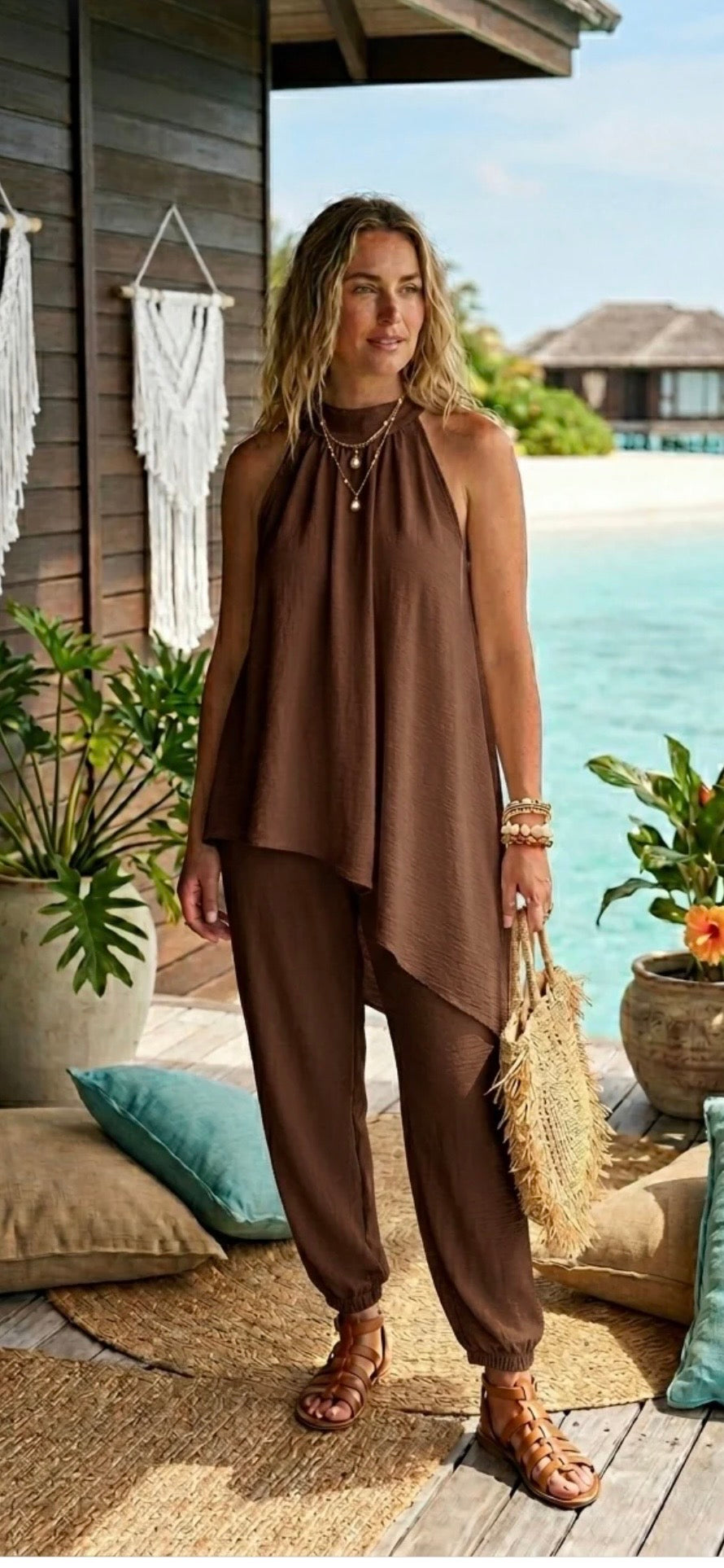 Woman in brown outfit standing by a poolside with plants and a wooden structure in the background