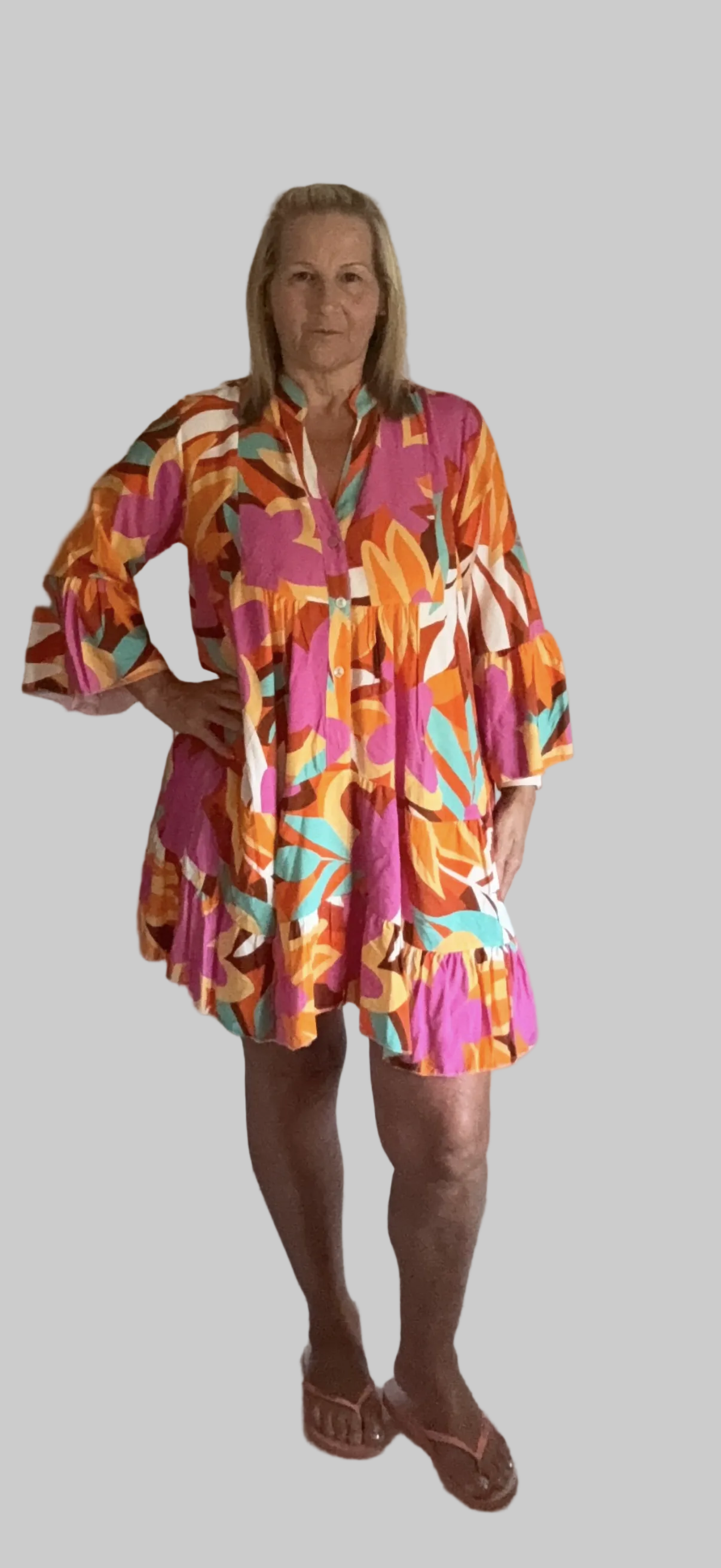 Woman wearing a colorful floral dress on a plain background