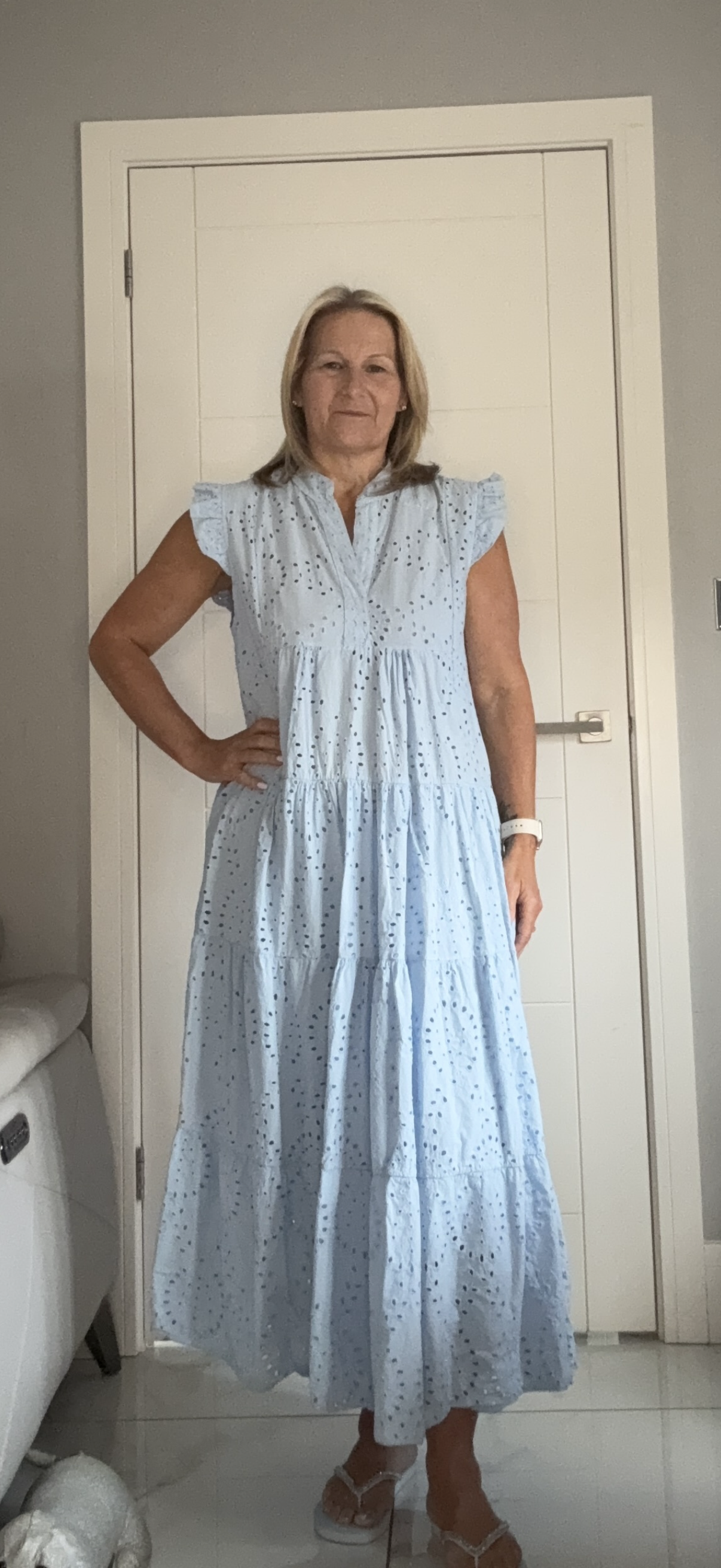 Woman wearing a light blue dress standing in a room with a white door.