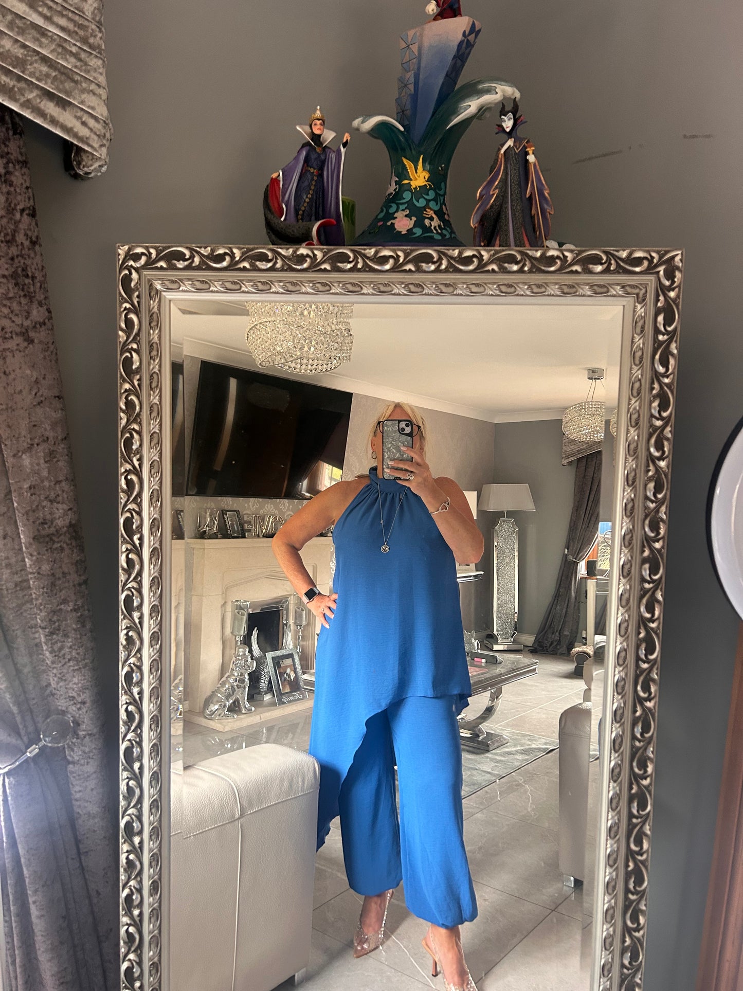 Person wearing a blue suit standing in front of a decorative mirror.