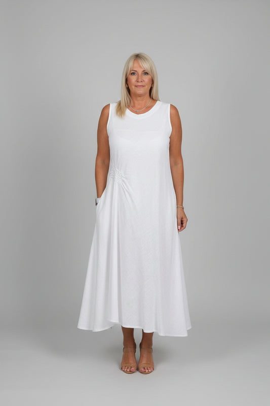 Person wearing a white dress standing in front of a decorative mirror.