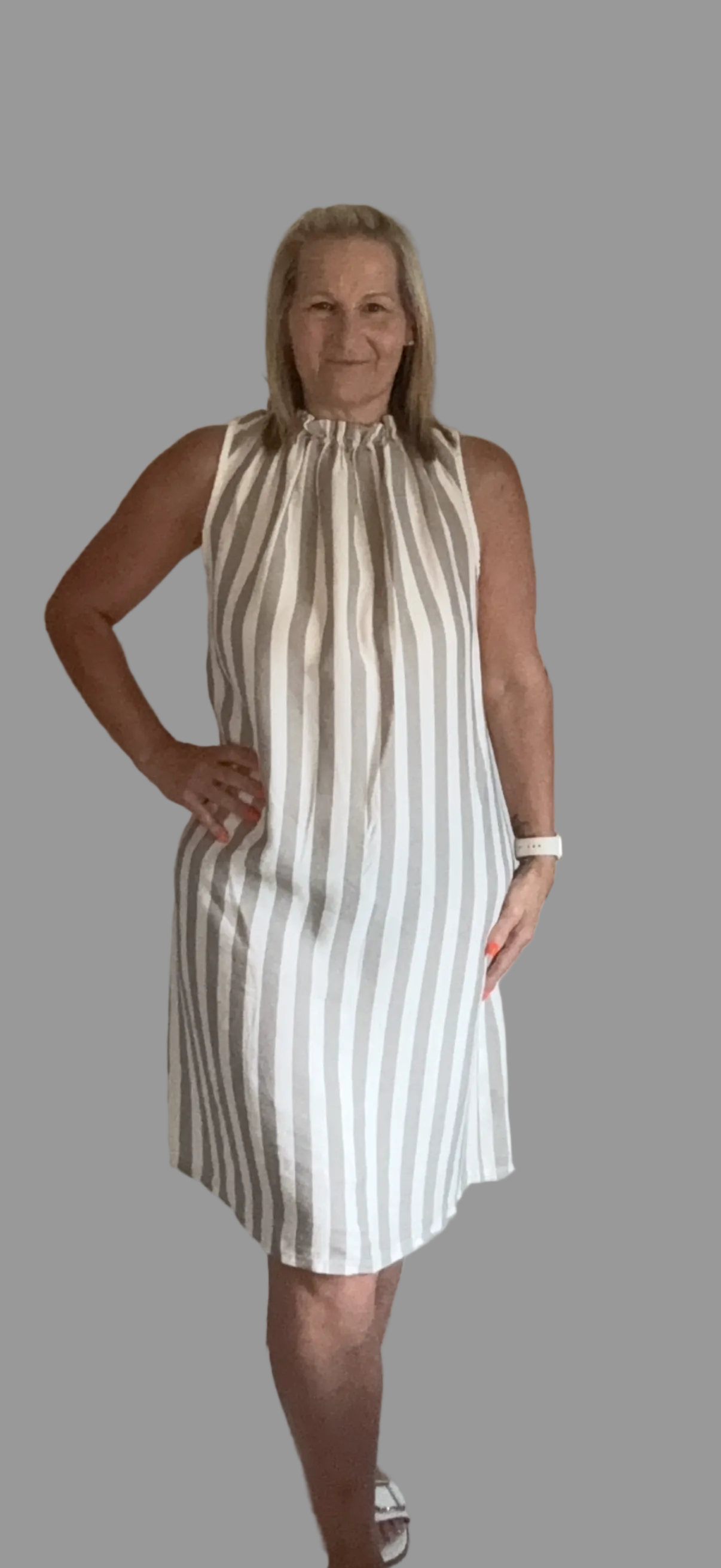 Woman wearing a sleeveless striped dress against a gray background