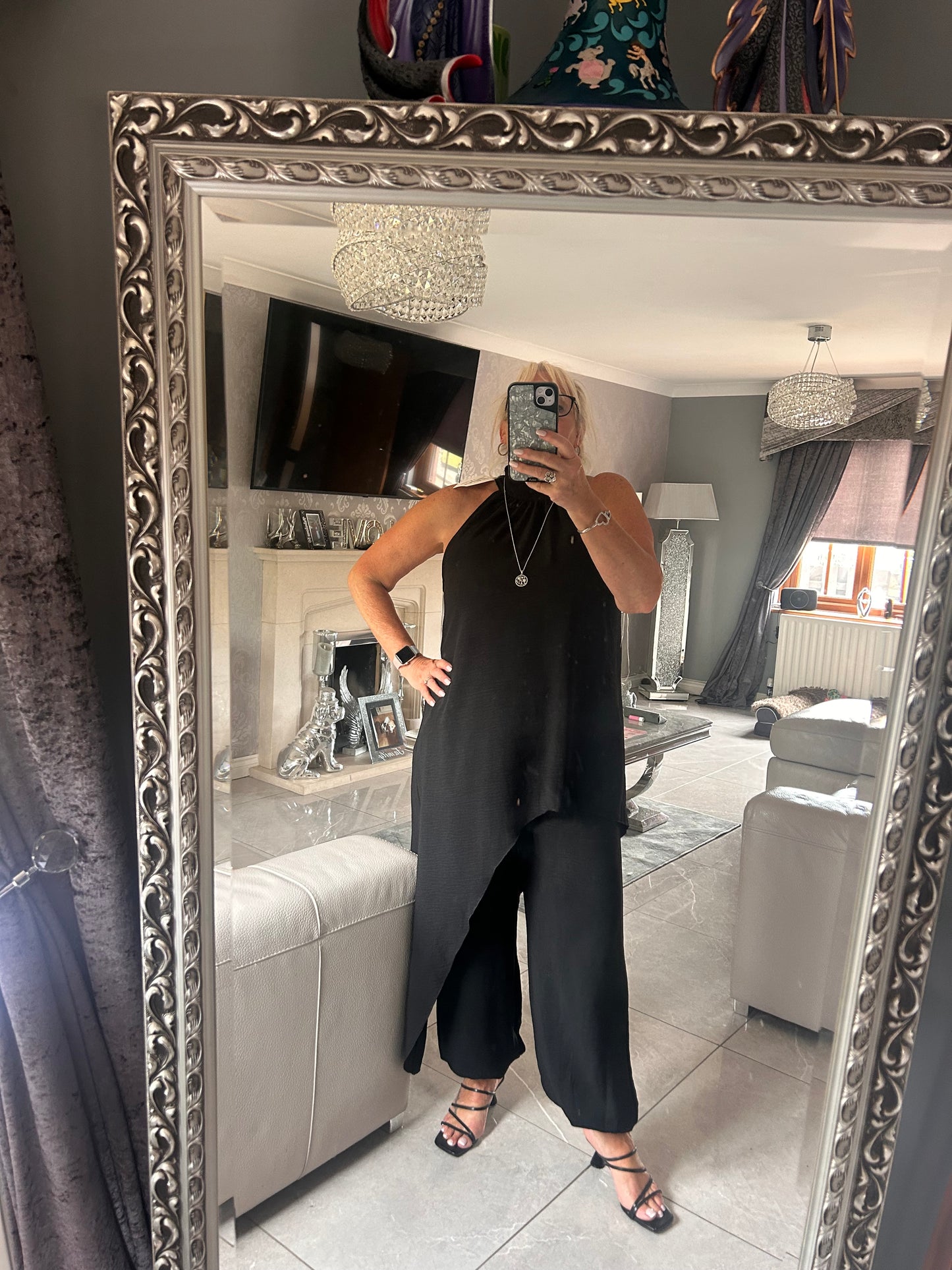 Person wearing a black outfit with a decorative mirror in a room.