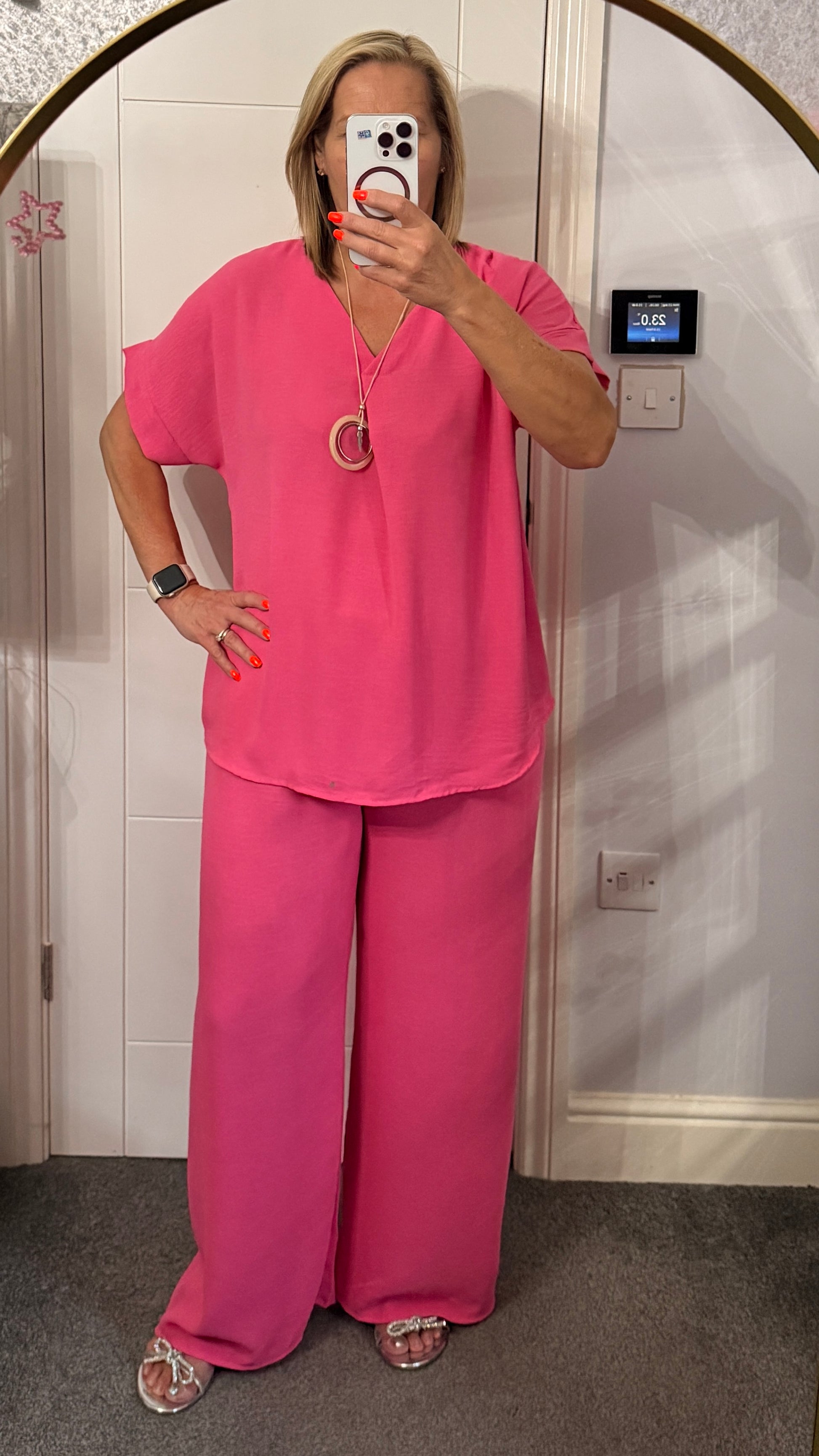 Person wearing a pink outfit taking a mirror selfie.