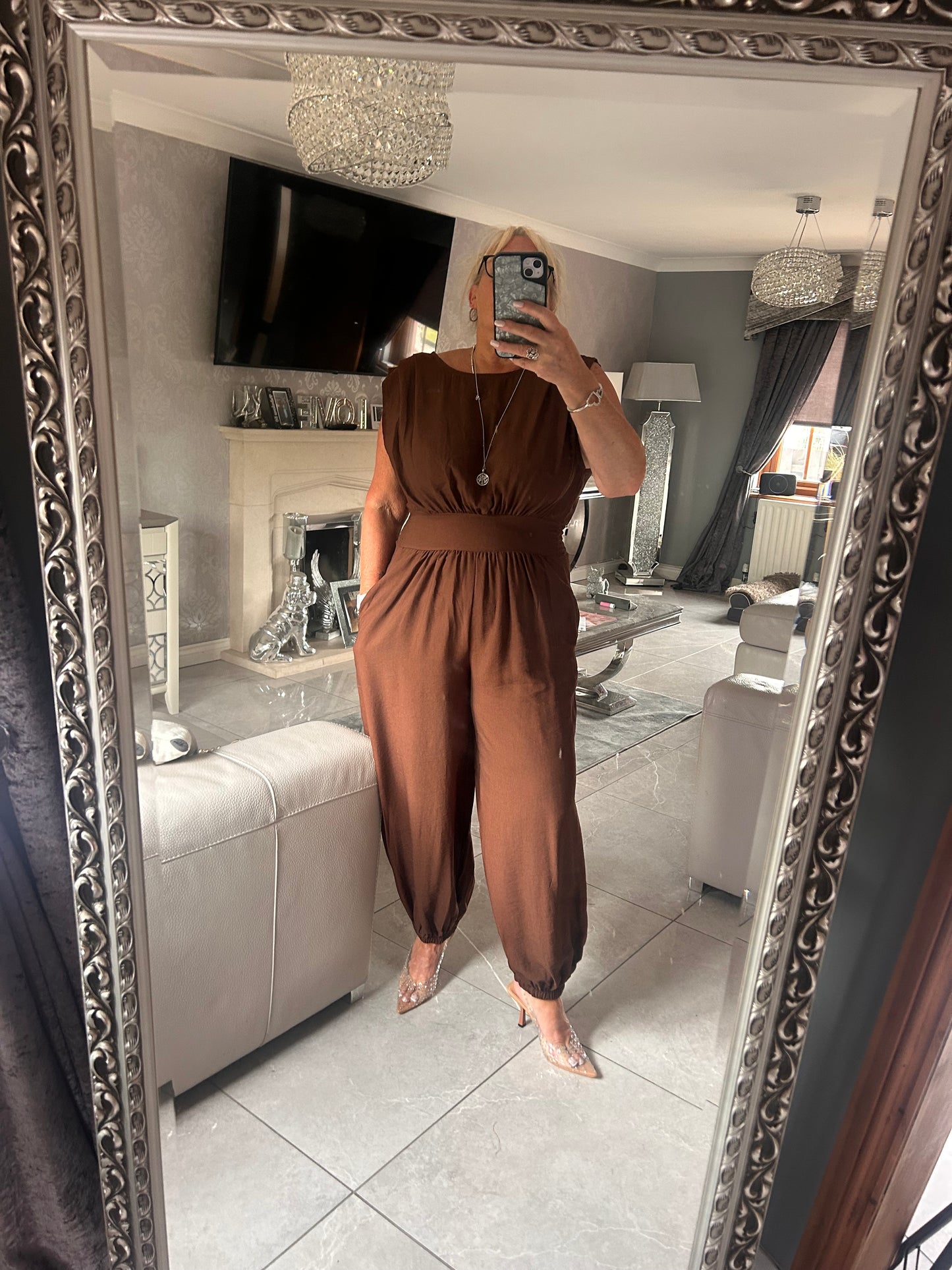 Person wearing a brown outfit taking a mirror selfie in an elegant interior setting.