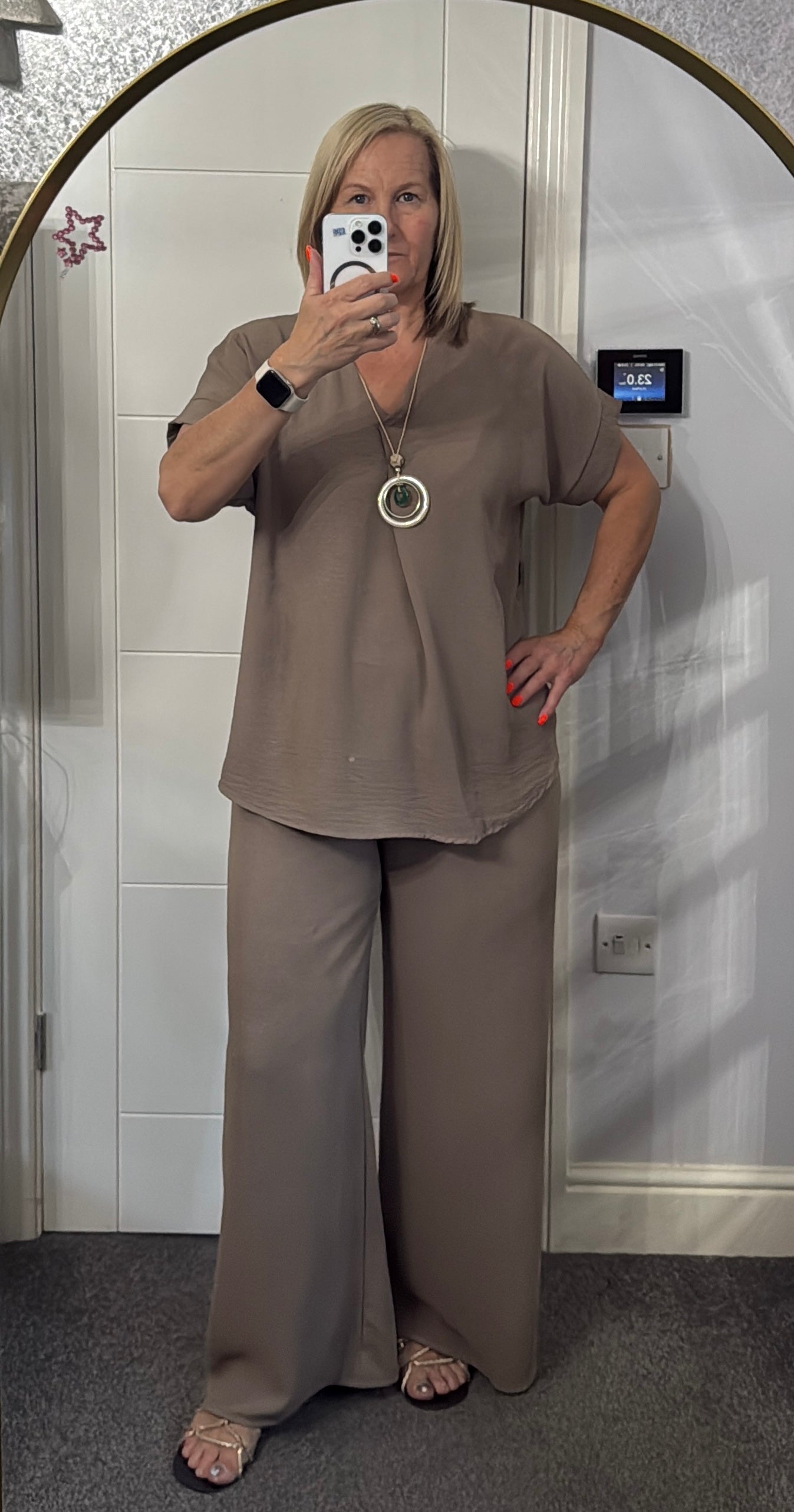 Woman taking a mirror selfie wearing a Taupe outfit ,