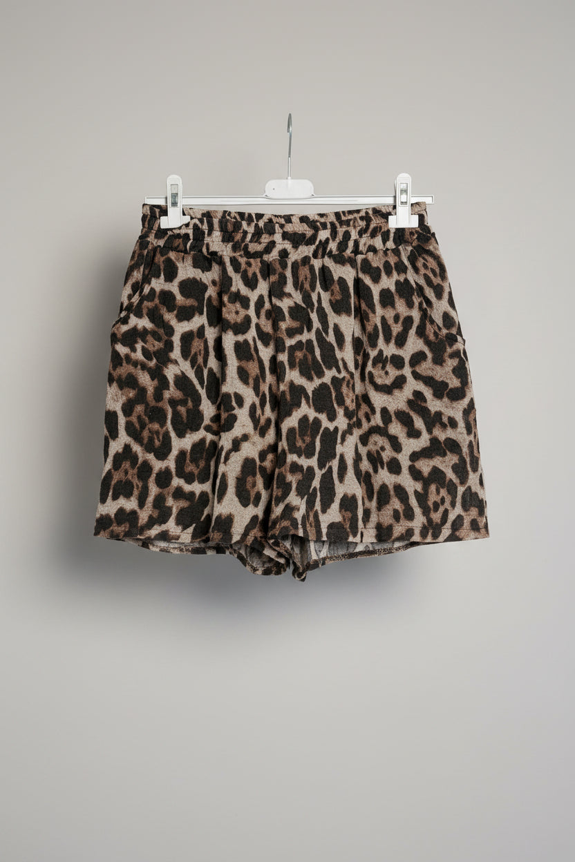 Leopard print shorts on a hanger against a white background