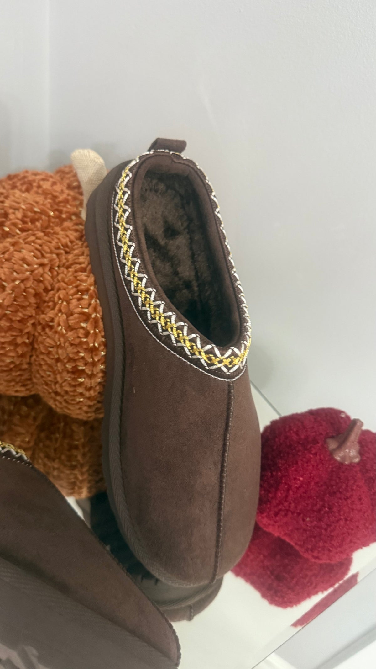 Brown slipper with decorative trim on a white background