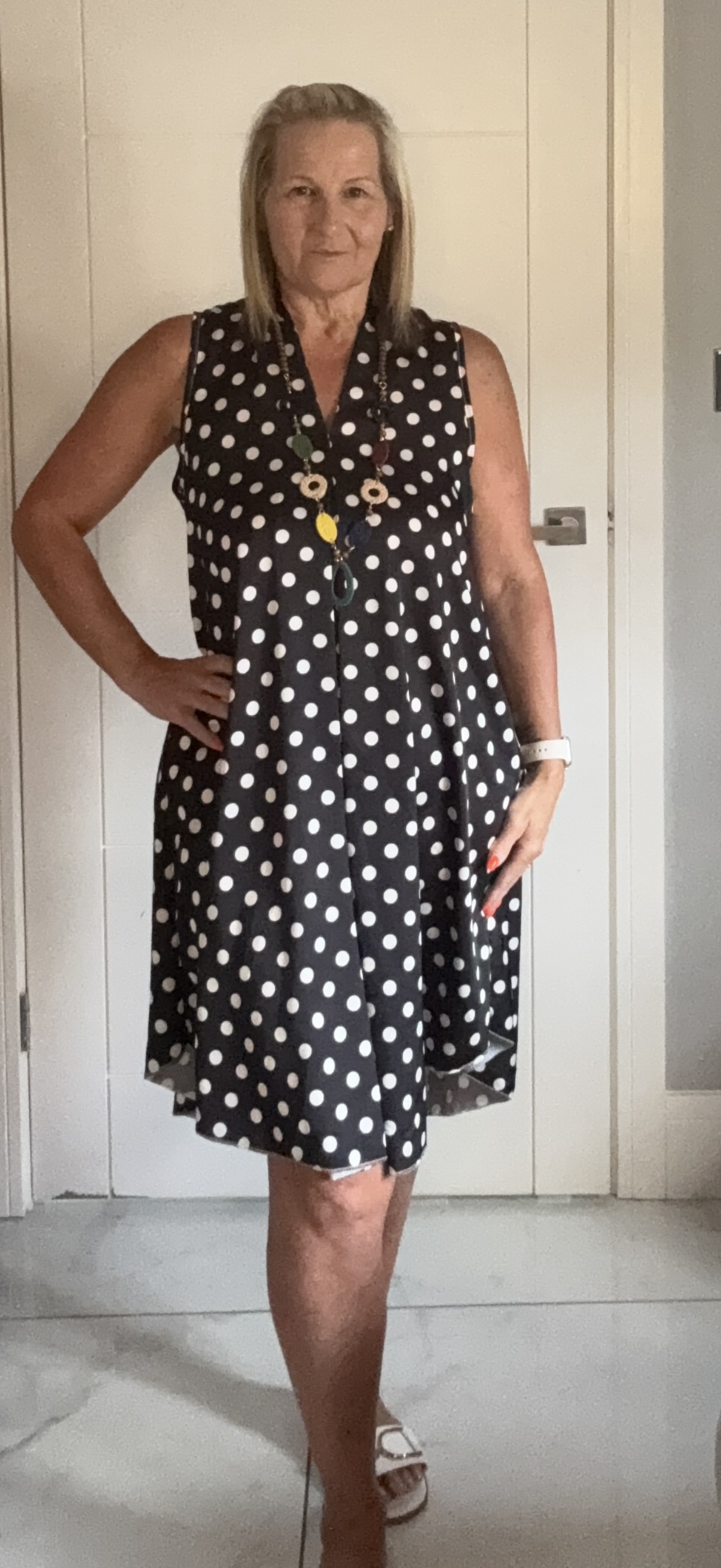 Women wearing black polka dot dress with white dots and necklace 