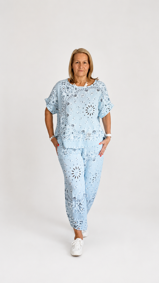 Woman wearing a light blue Paisley print outfit on a white background