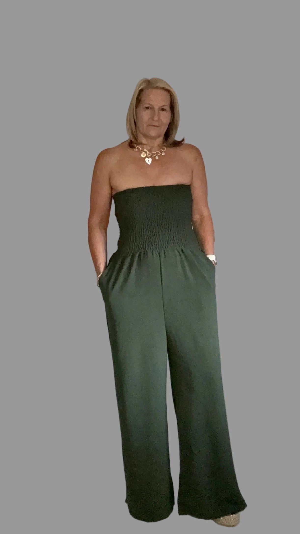 Woman wearing a green strapless jumpsuit on a gray background