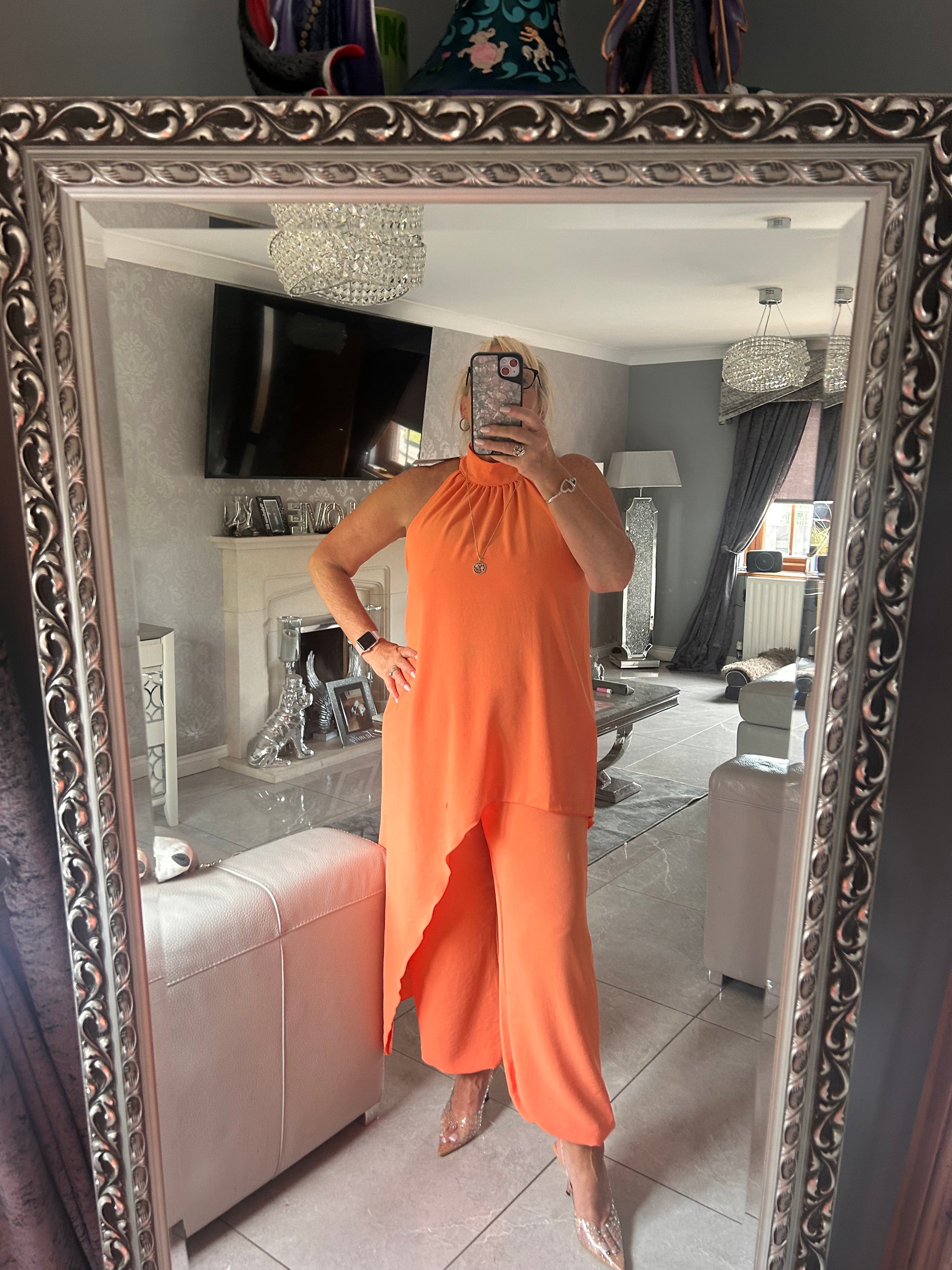 Person wearing an orange suit standing in front of a decorative mirror.