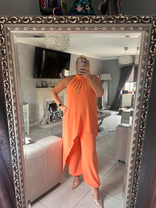 Person wearing an orange suit standing in front of a decorative mirror.