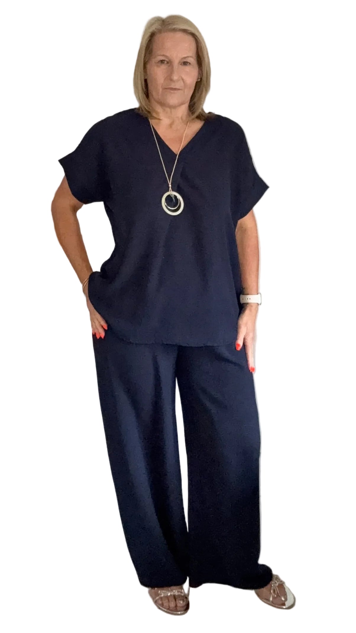 Woman in navy blue outfit standing in a room with a white BACKGROUND