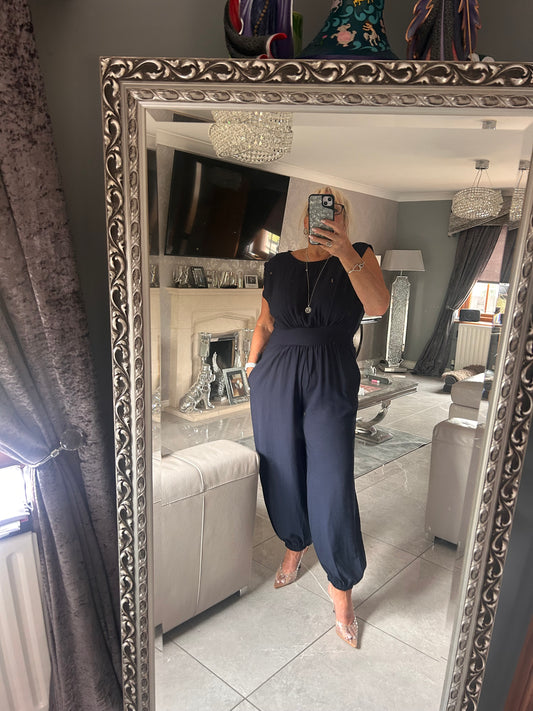 Person wearing a dark blue outfit standing in front of an ornate mirror.