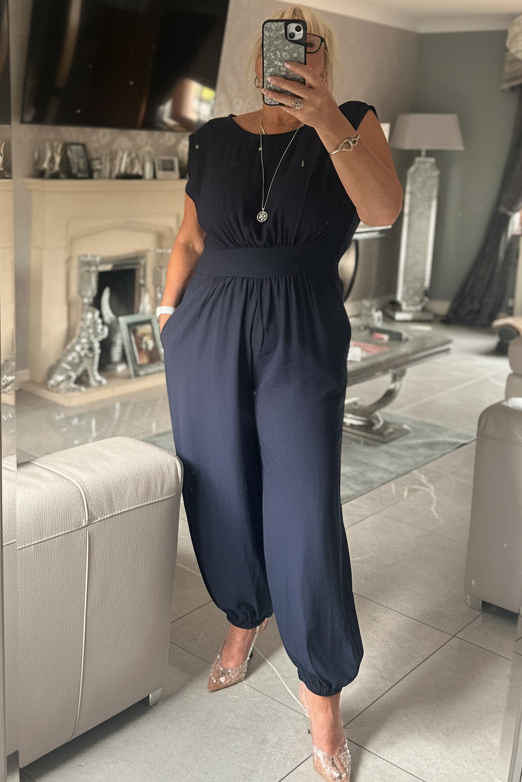 Person wearing a navy blue jumpsuit in a living room.