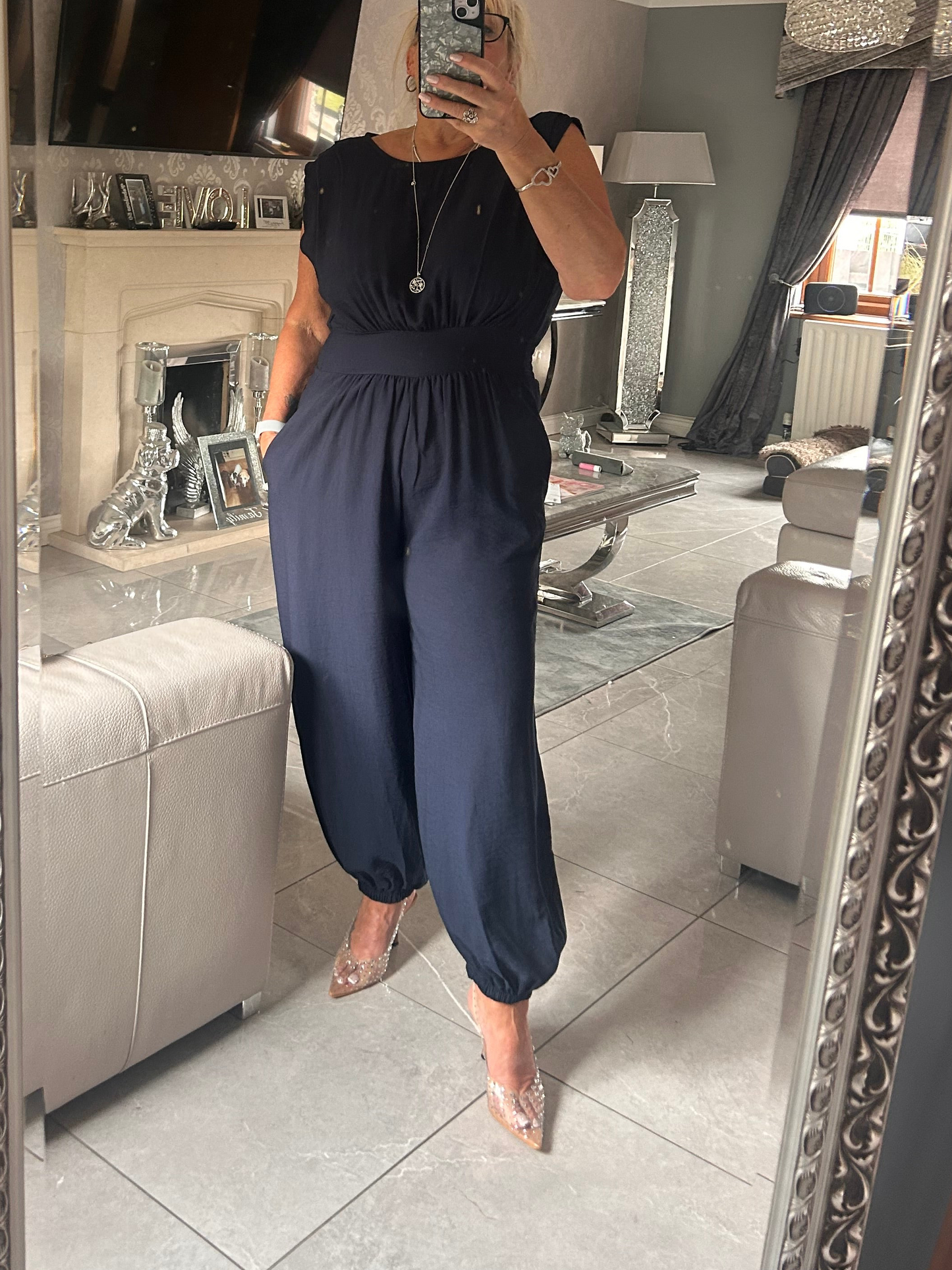 Person wearing a navy blue jumpsuit in a living room setting.