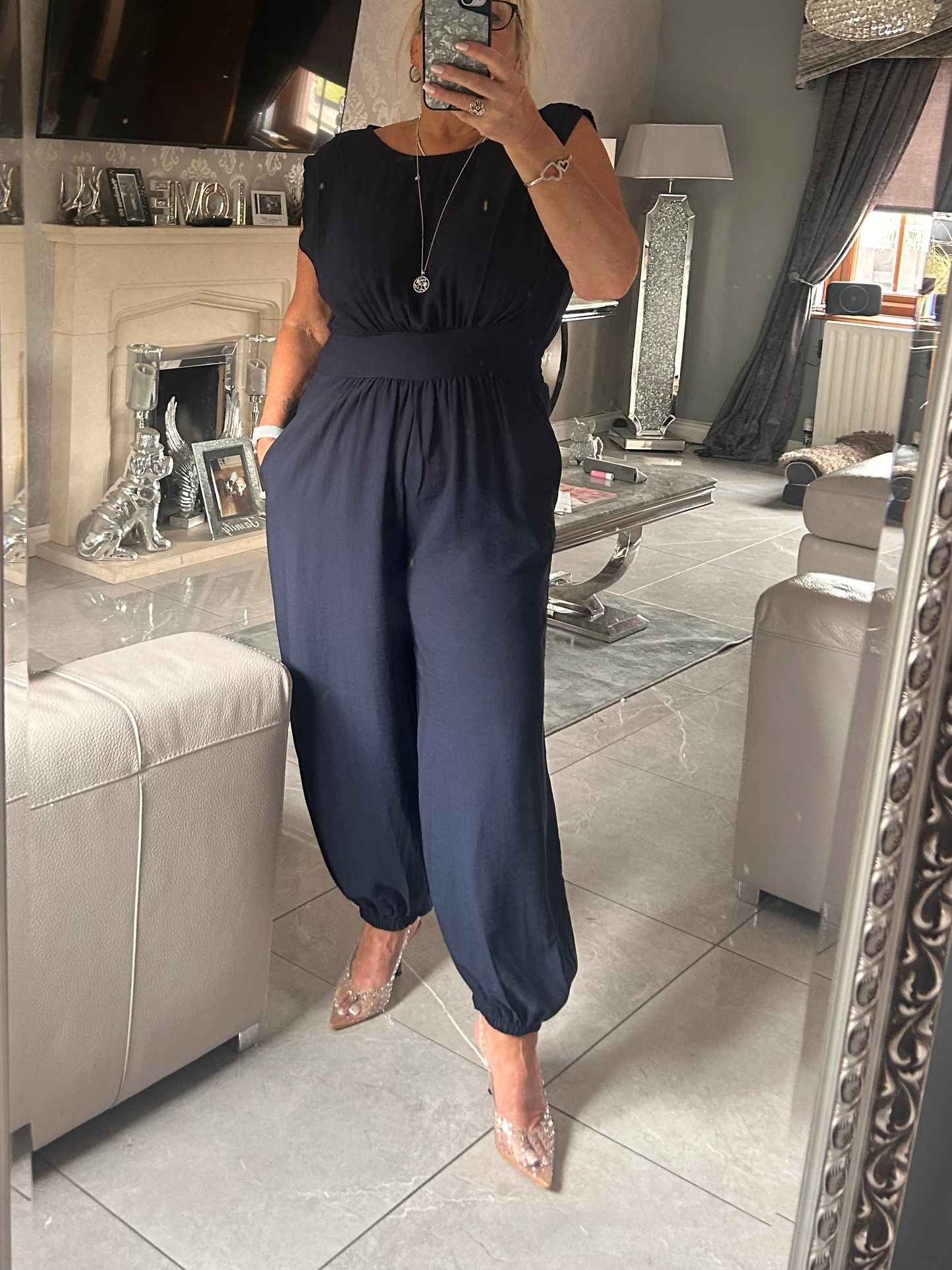 Person wearing a navy blue jumpsuit in a living room.