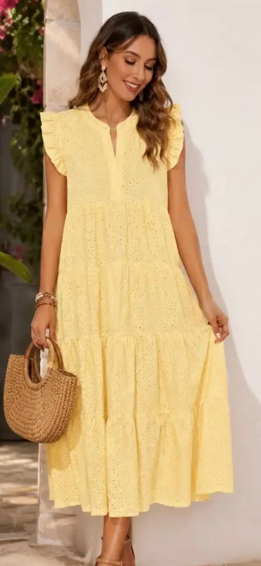 Woman wearing a yellow dress holding a woven handbag against a white background