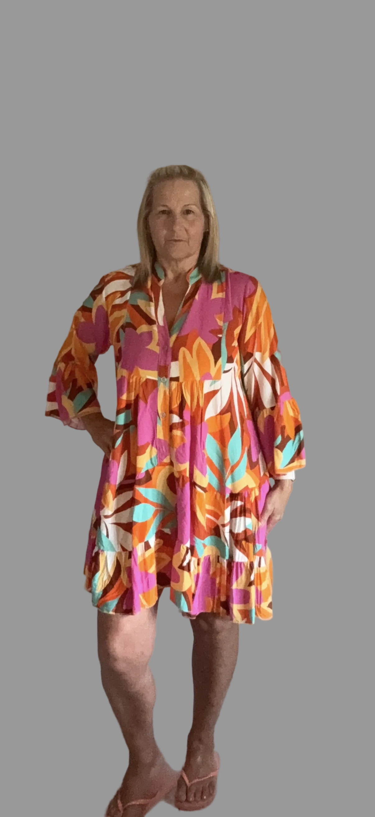 Woman wearing a colorful patterned dress on a gray background