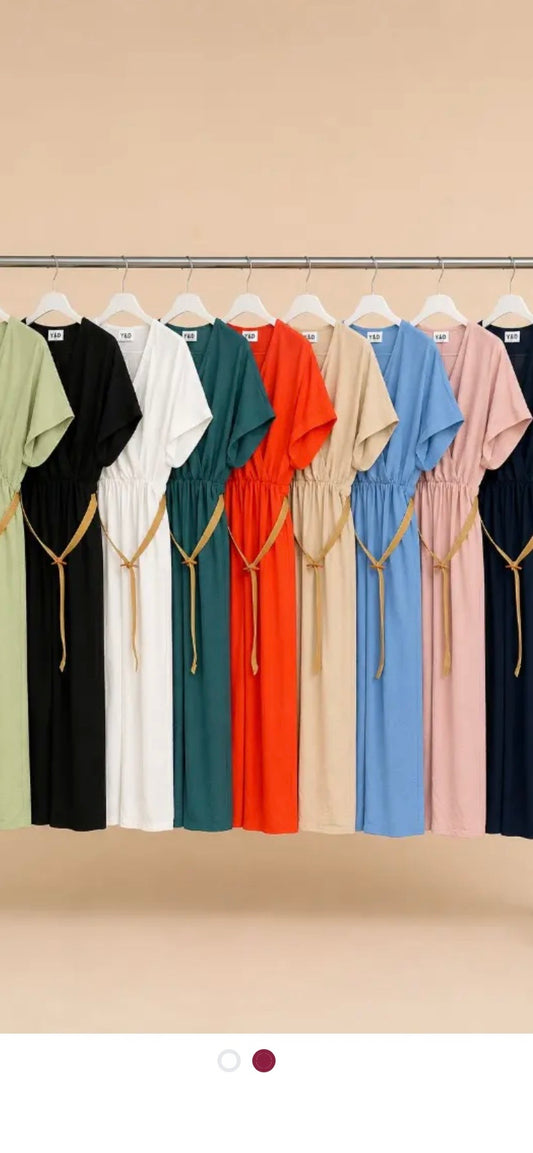 Row of colorfull jumpsuits on hangers against a beige wall