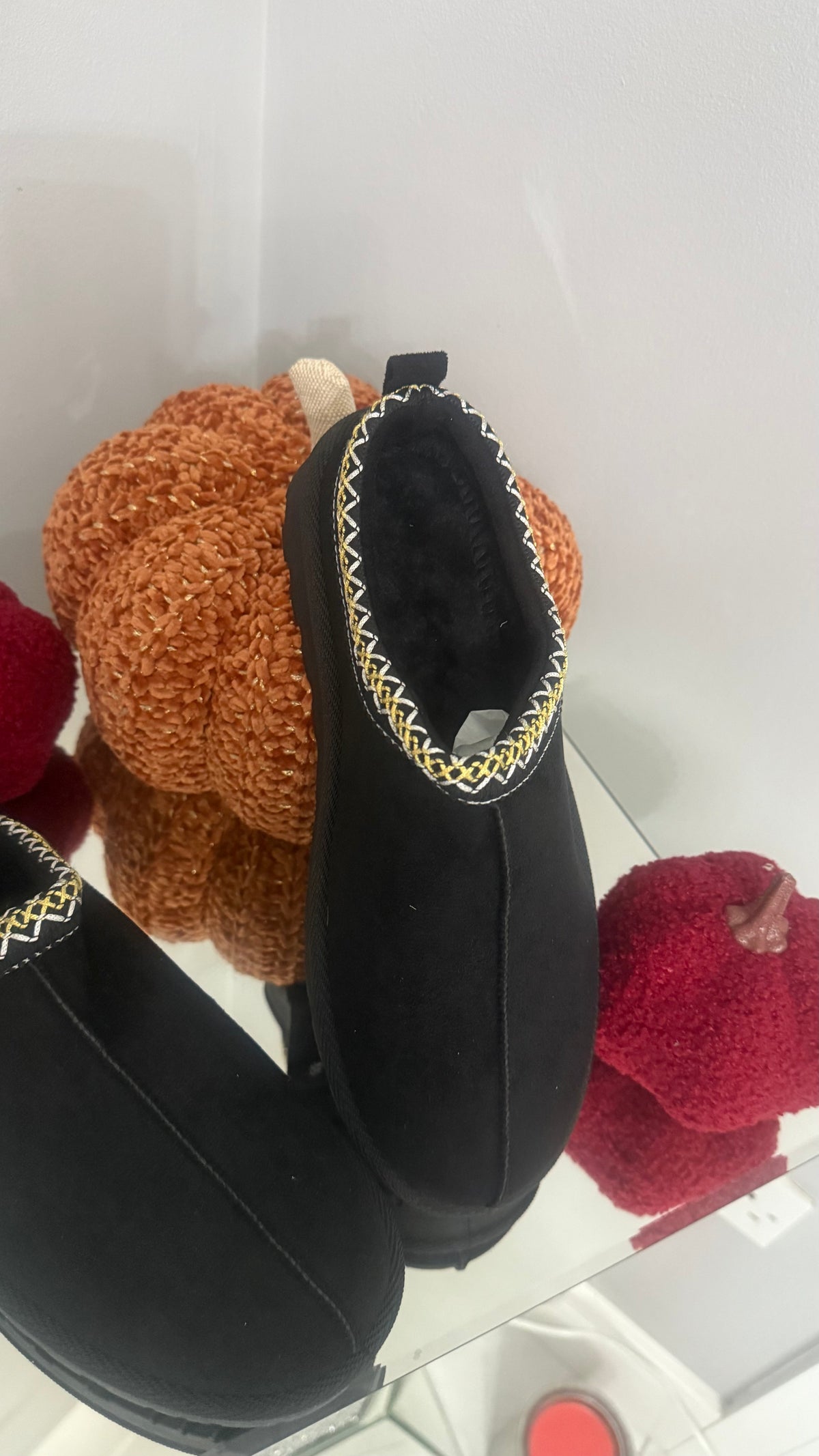 Black slippers with decorative trim on a white background