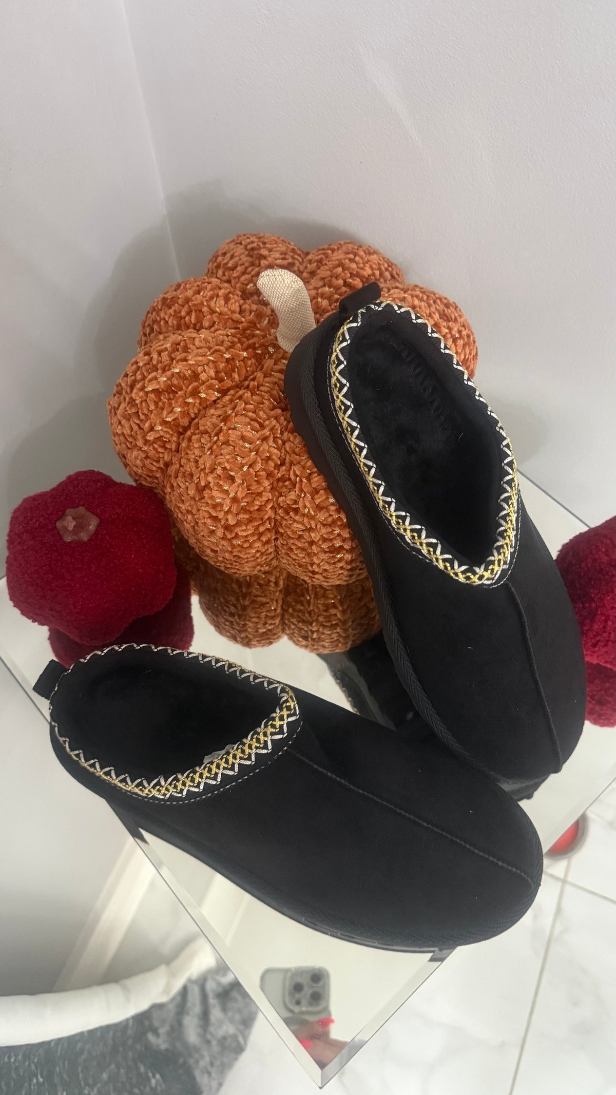 Pair of black slippers with decorative trim on a white background