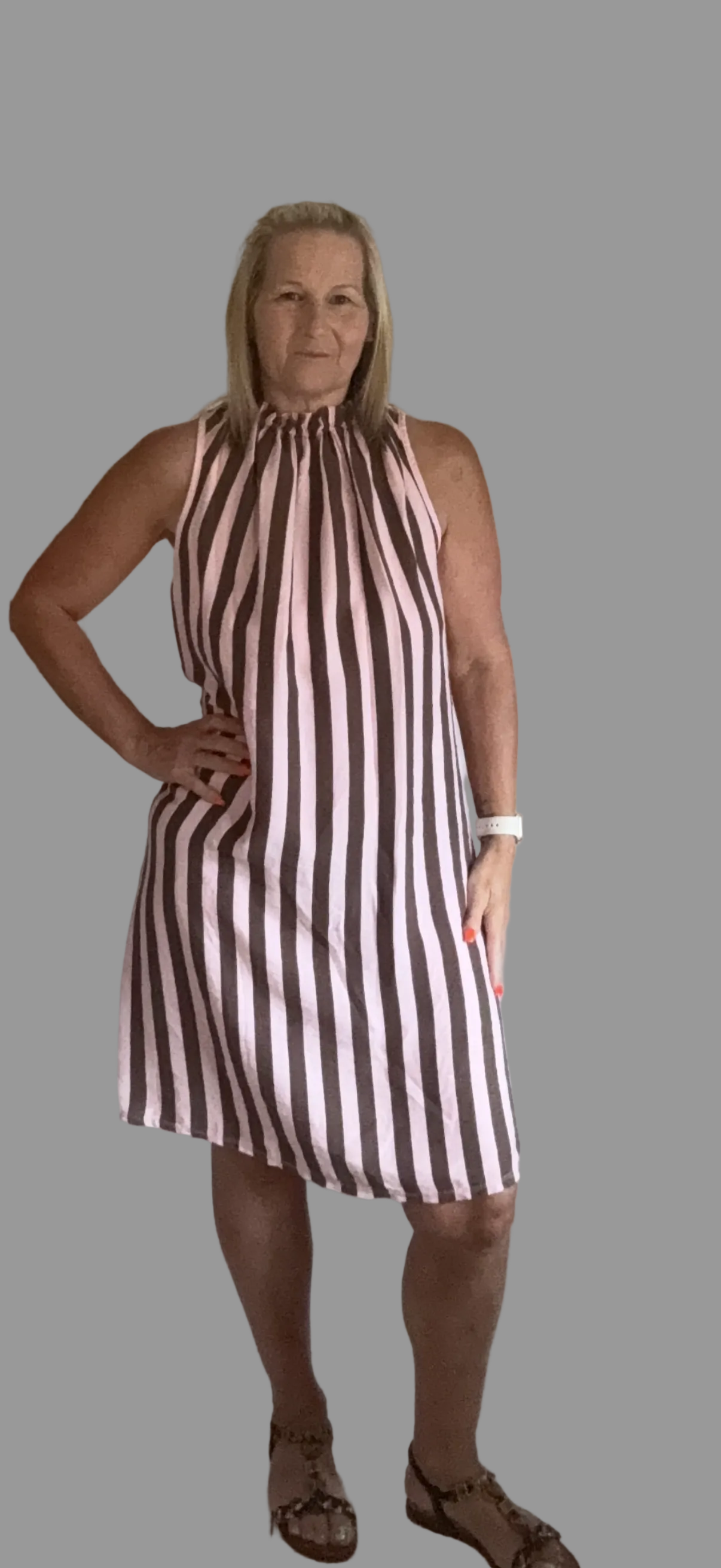 Woman wearing a brown and white striped dress against a gray background