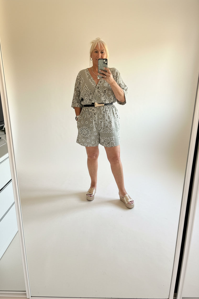 Person wearing a Taupe Millie playsuit taking a mirror selfie in a minimalistic room.
