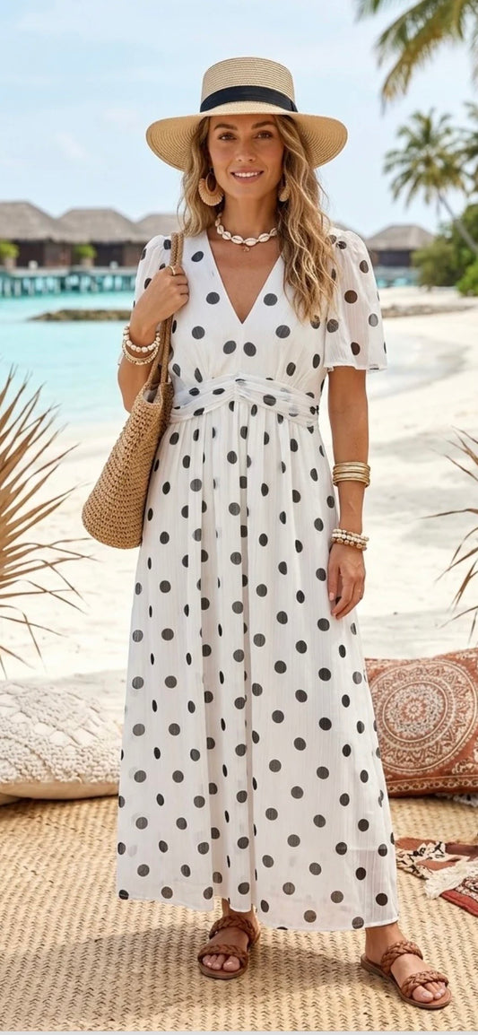 Woman in a polka dot dress and hat by a beach