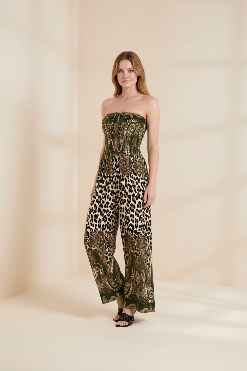 A woman modeling a strapless wide-leg jumpsuit with an abstract green, brown, and black pattern, paired with black sandals, on a plain white background.