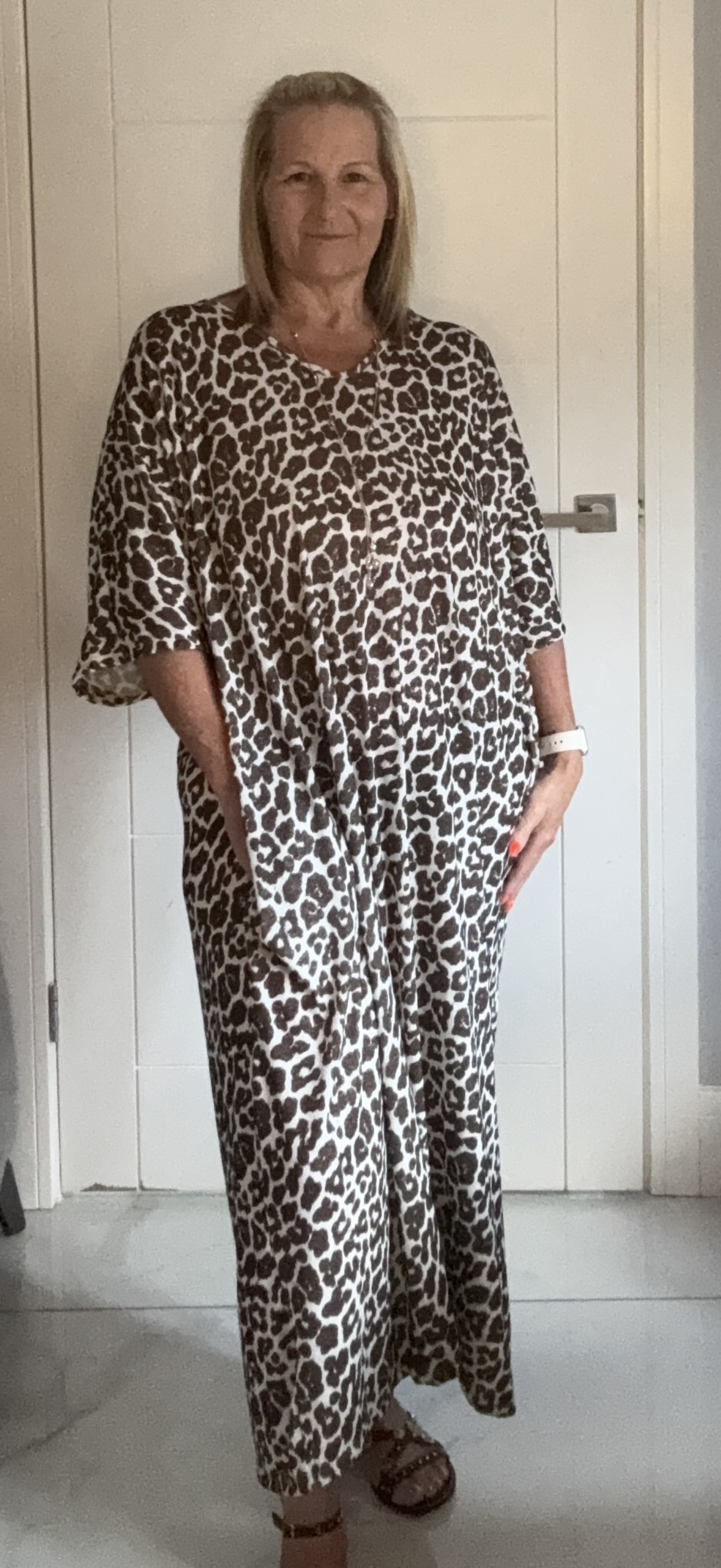 Person wearing a leopard print outfit standing in a room with white walls and a door.