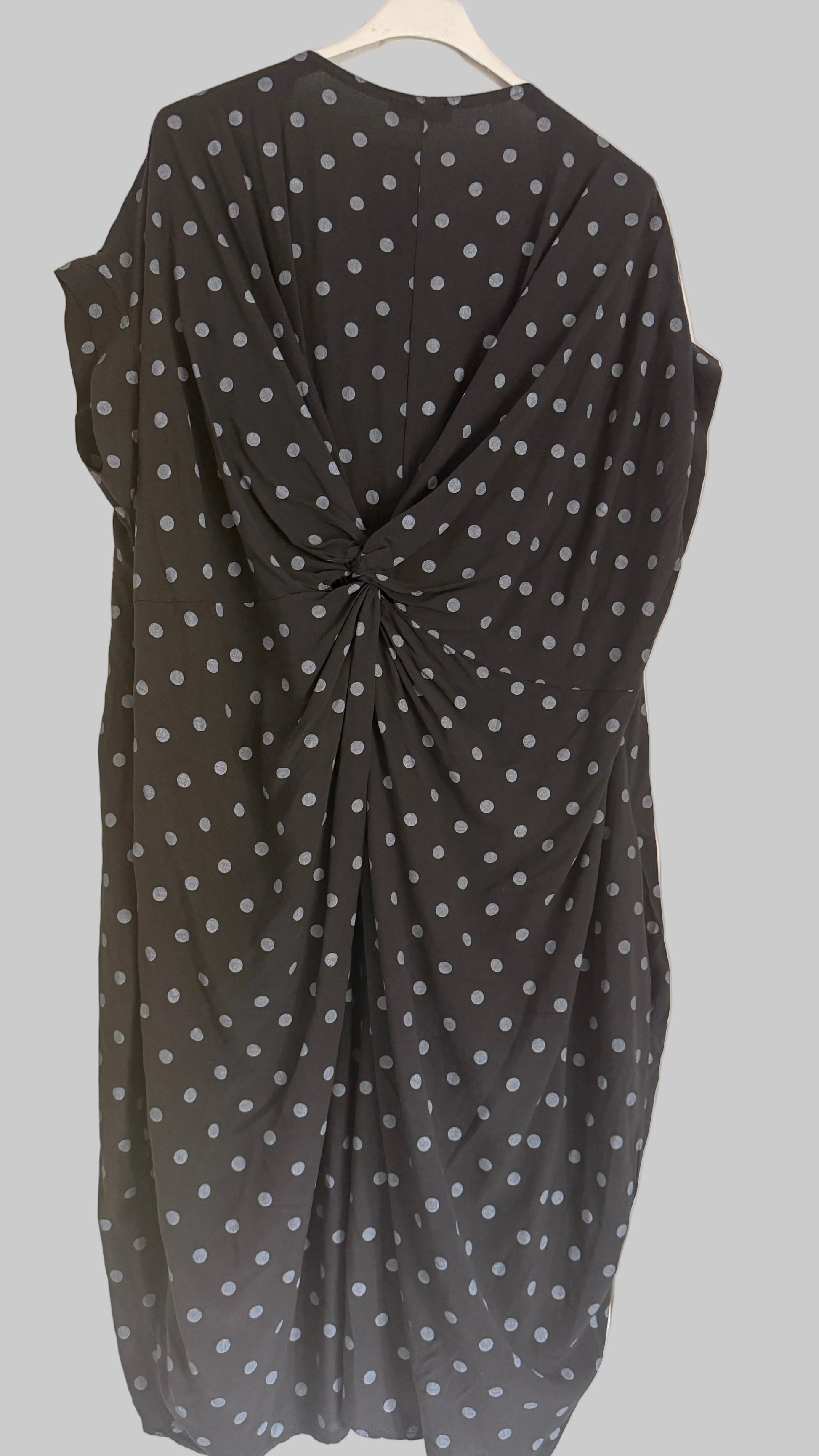 Black dress with white polka dots hanging on a door