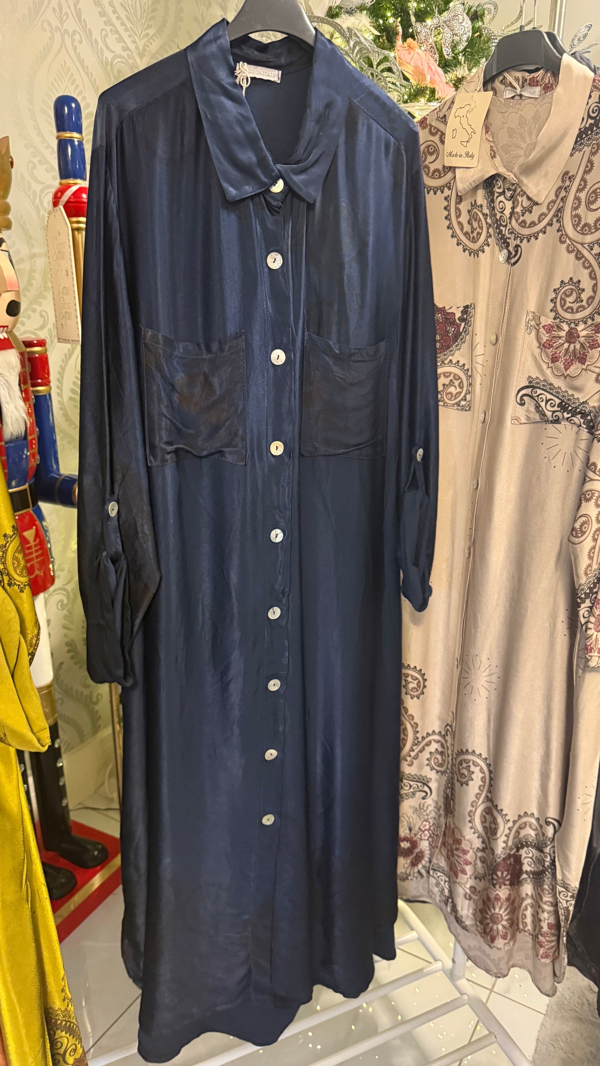 Navy blue dress with white buttons on a rack in a store setting