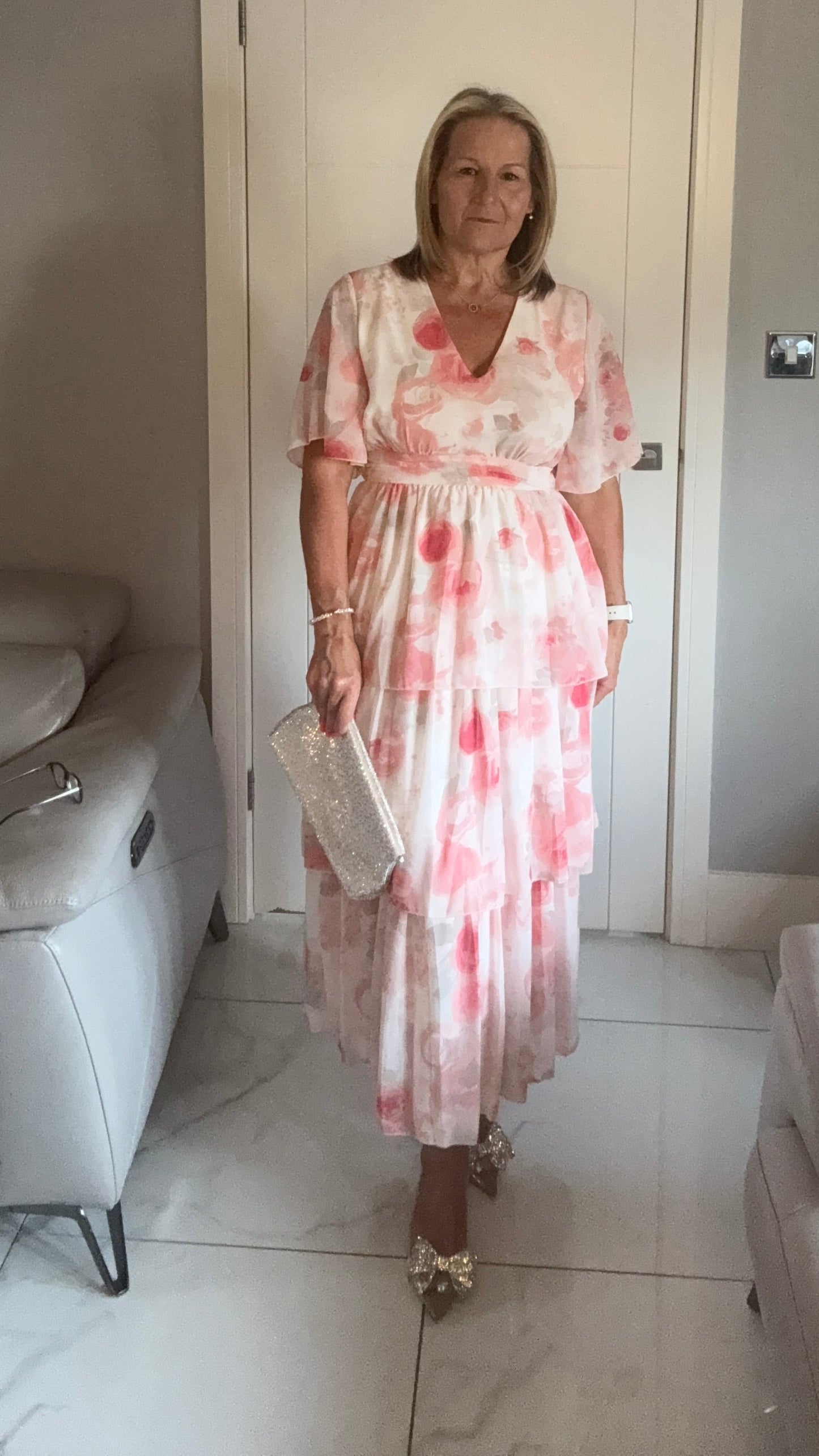 Woman in a floral dress standing in a room with a couch and door.
