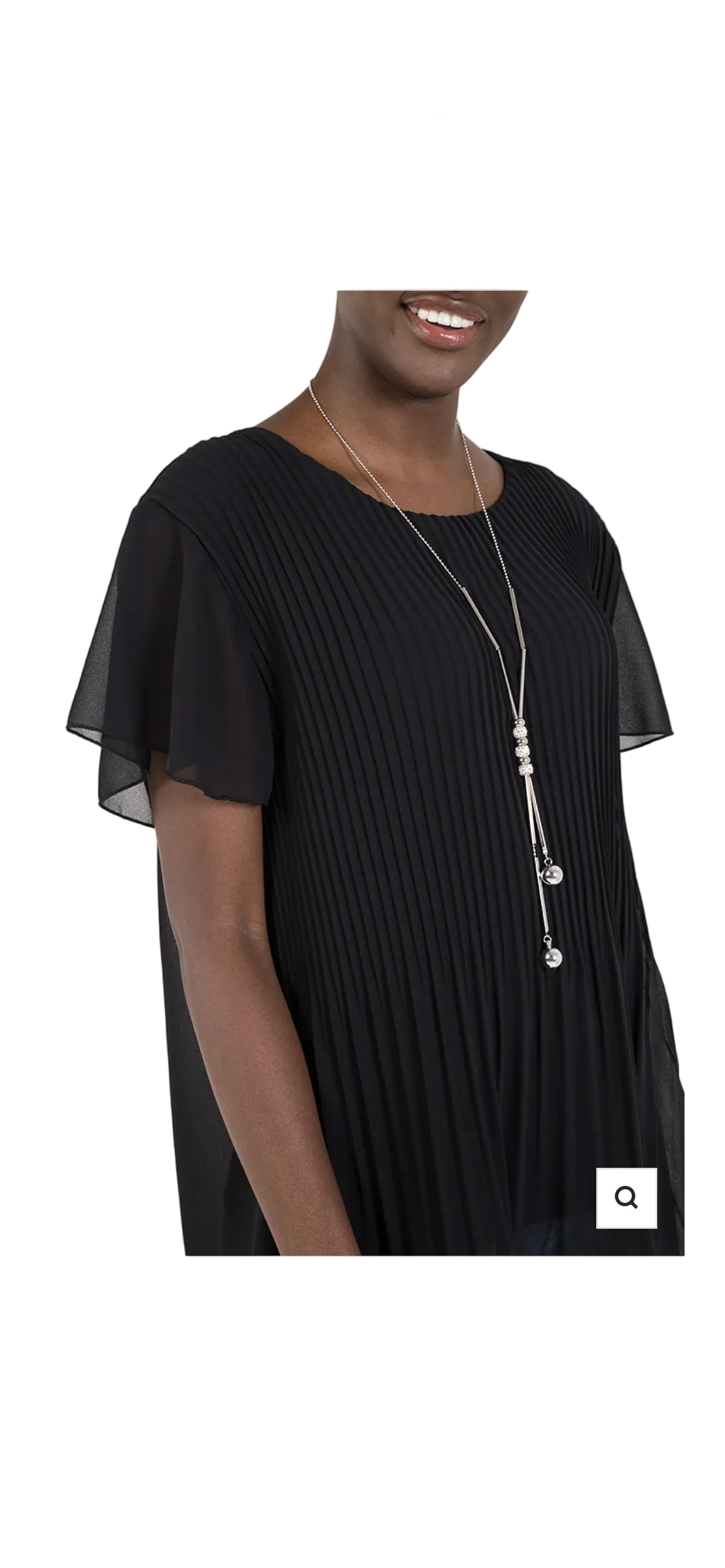 A woman wearing a black pleated short-sleeve top with sheer flutter sleeves and a long silver-toned pendant necklace, shown against a plain white background.