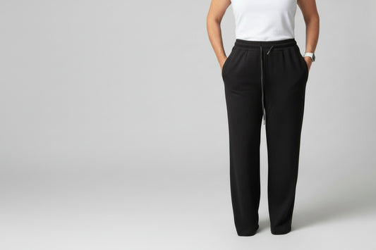 Person wearing black pants and a white top on a plain background
